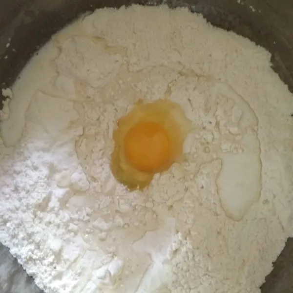 Tambahkan telur ayam dan tuang susu cair sedikit demi sedikit, jika di rasa adonan masih belum kalis bisa ditambahkan lagi susunya, jika dirasa sudah pas, stop pemberian susu, uleni hingga kalis.