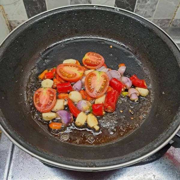 Iris kasar tomat, cabe merah, bawang putih dan bawang merah. Kemudian goreng sampai layu. Angkat dan taruh ke dalam cobek.