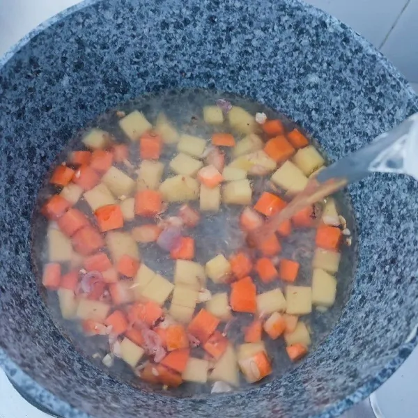 Kemudian masukkan 300 ml air, rebus hingga wortel dan kentang empuk.