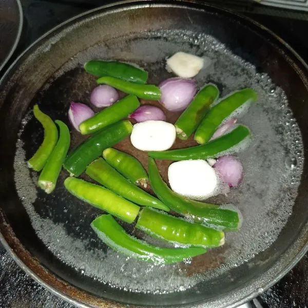 Rebus cabai hijau, bawang merah dan bawang putih sampai layu.