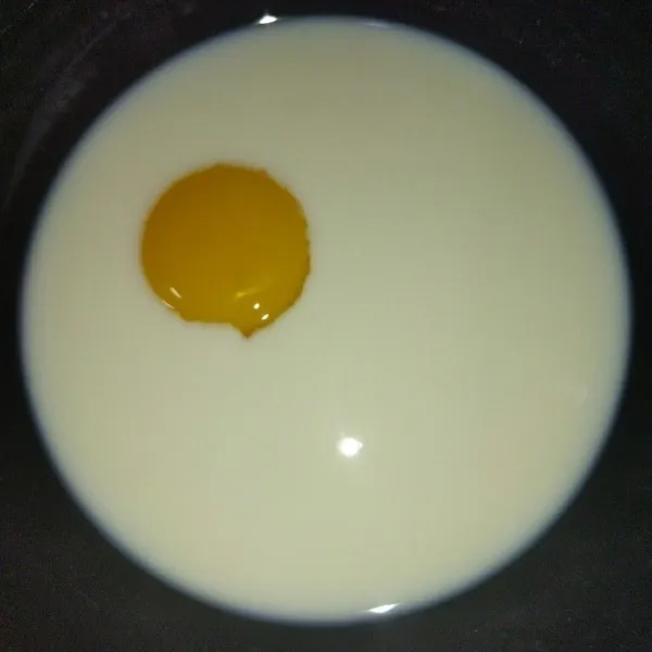 Siapkan mangkuk, masukkan sisa susu cair 100 ml dan kuning telur, lalu kocok.