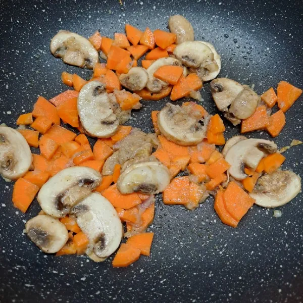 Masukkan wortel dan jamur kancing, tumis sampai layu. Tuang air, masak sampai mendidih.