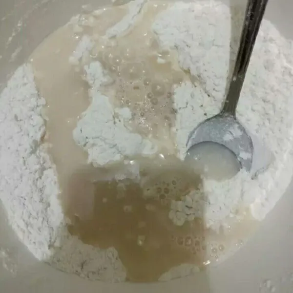 Masukkan larutan air ragi ke dalam campuran tepung lalu uleni hingga kalis.