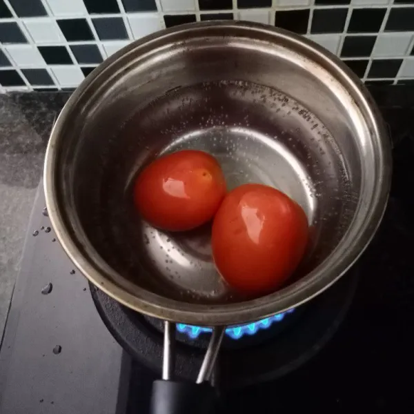 Didihkan air. Rebus tomat hingga kulitnya mengelupas.