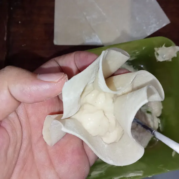 Ambil kulit pangsit, tambahkan adonan dan kuncupkan.