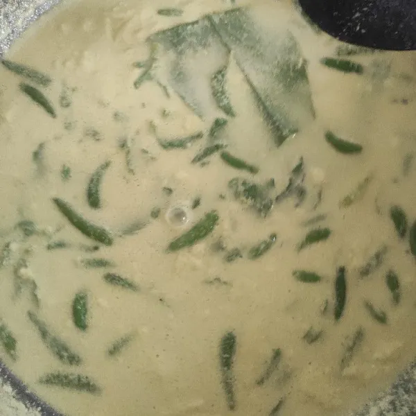 Masukkan santan, bumbu halus, cabe rawit, dan dedaun ke dalam wajan.