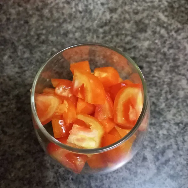 Siapkan gelas, tuang potongan pepaya dan tomat ke dalamnya.