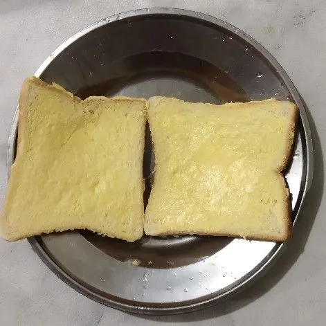 Siapkan roti tawar lalu oles dengan margarin.