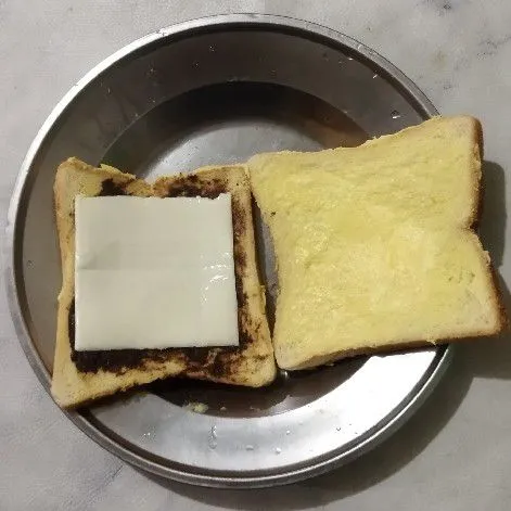 Tambahkan keju slice di atas roti.