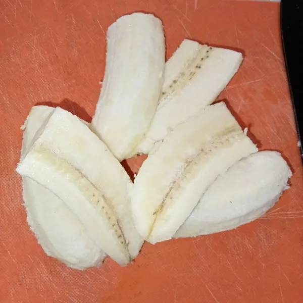 Kupas pisang kemudian belah dan potong menjadi empat bagian.