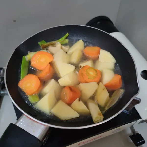 Masukkan air, bunga lawang, wortel dan kentang, kemudian masak hingga wortel dan kentang matang.