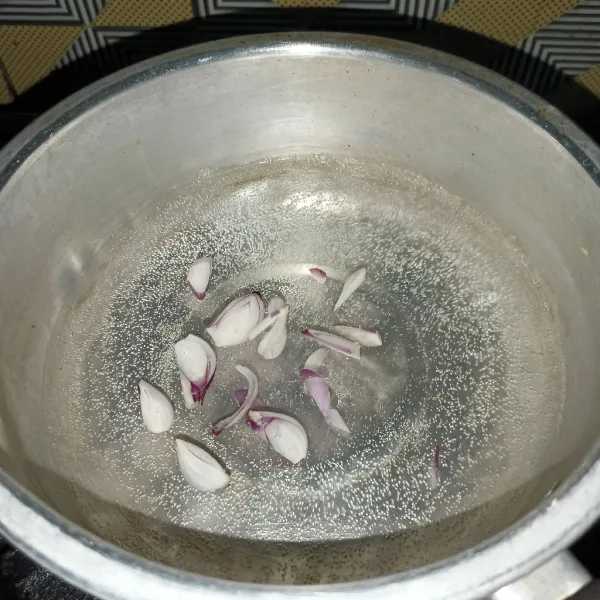 Rebus air dan irisan bawang merah di panci.