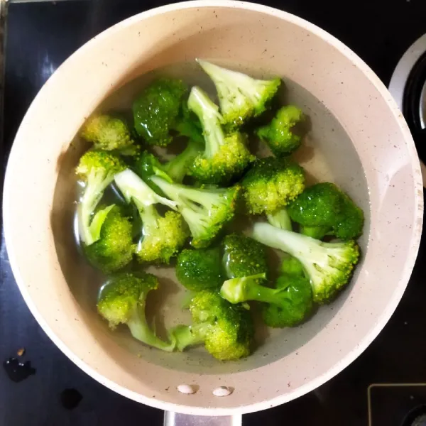 Panaskan air dalam panci hingga mendidih lalu tambahkan garam didalamnya. Masukkan brokoli ke dalamnya lalu rebus hingga matang selama tiga menit lalu angkat dan sisihkan.