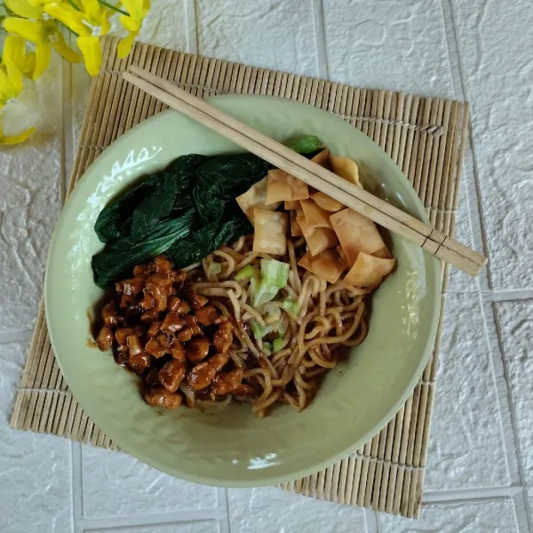 Tambahkan sawi rebus, tumisan ayam, pangsit goreng dan daun bawang. Sajikan hangat.