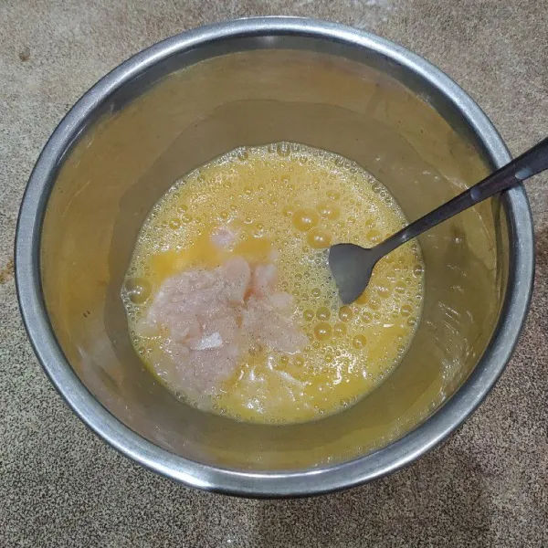 Masukkan daging ayam cincang ke dalam kocokan telur, tambahkan garam, kaldu jamur dan lada bubuk. Kocok kembali hingga merata.