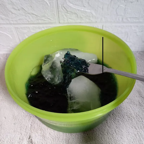 Masukkan es batu ke dalam wadah. Tuang jelly telang. Kemudian aduk-aduk.