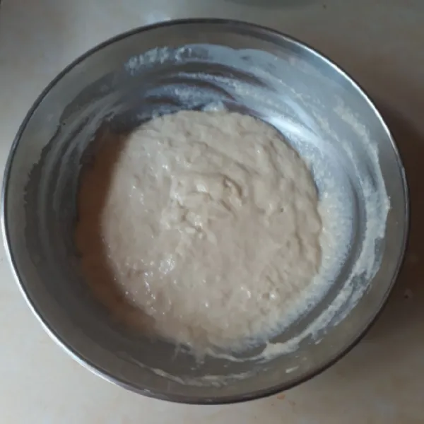 Tambahkan bahan biang ke dalam tepung, sedikit demi sedikit sambil diaduk hingga rata.