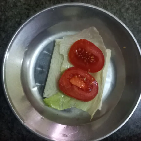 Tata lettuce dan irisan tomat di atas roti tawar, tutup dengan roti tawar lagi dan tumpuk kembali ke atas hingga selesai.