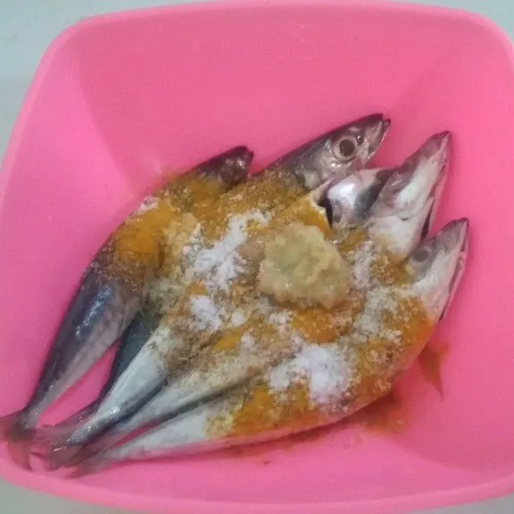 Haluskan bawang putih, taburkan ke ikan bersama ketumbar bubuk, kunyit bubuk dan garam.