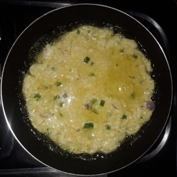 Panaskan minyak, goreng adonan telur dengan api sedang sampai sisi bawah kering.