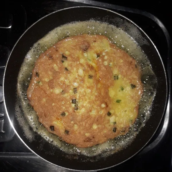 Balik telur secara perlahan, goreng sampai kedua sisi kering dan matang. Angkat, potong sesuai selera lalu sajikan.