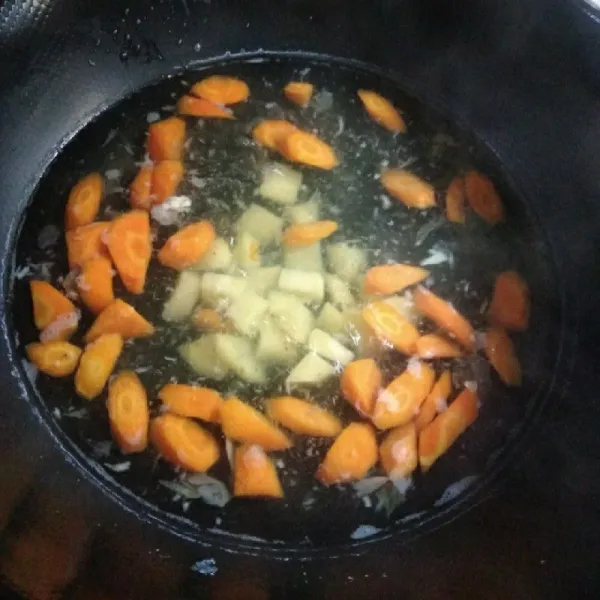 Siapkan air, masak sampai panas. Masukkan bumbu halus ke dalam air, tambahkan wortel dan kentang. Masak sampai setengah matang.