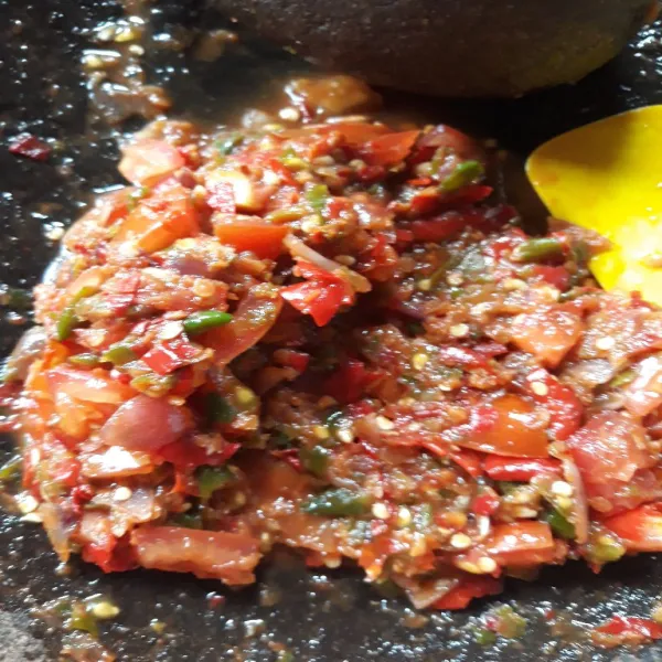 Tambahkan penyedap rasa dan irisan tomat. Siram minyak panas sisa menggoreng ayam. Lalu aduk rata semuanya.