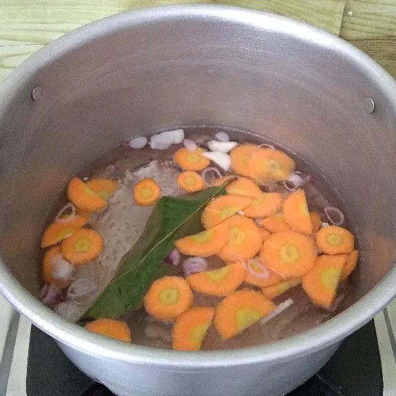 Rebus air hingga mendidih. Masukkan bumbu iris, wortel, dan daun salam. Masak hingga wortel empuk.