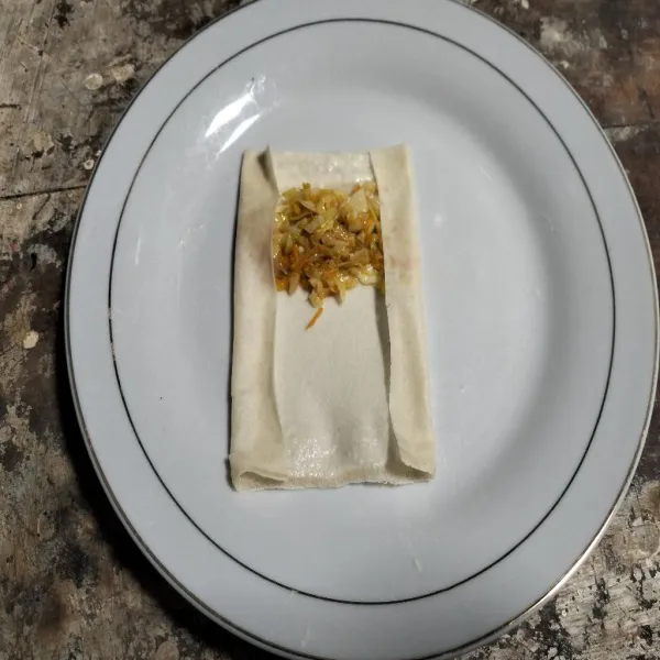 siapkan kulit lumpia, ambil satu sendok sayuran letakkan di ujung seperti pada gambar. Oleskan tepian kulit lumpia dengan adonan tepung sebagai perekat, lipat lalu gulung seperti sosis solo.