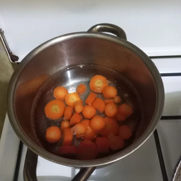 Didihkan air pada panci, masukkan irisan wortel, masak hingga setengah matang.