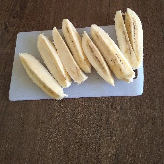 Kupas dan potong pisang kepok menjadi beberapa bagian.