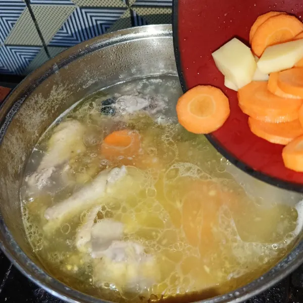 Masukkan kentang dan wortel, masak sampai tulangan ayam matang.