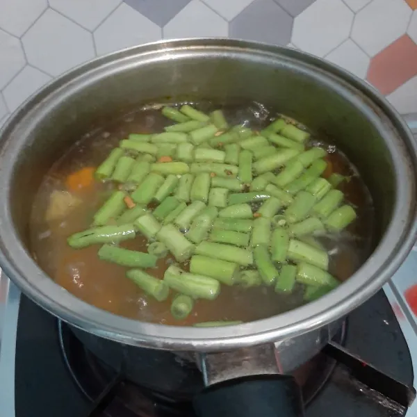 Masukkan wortel, kemudian kentang, lalu buncis. Masukkan juga irisan daun bawang dan seledri.