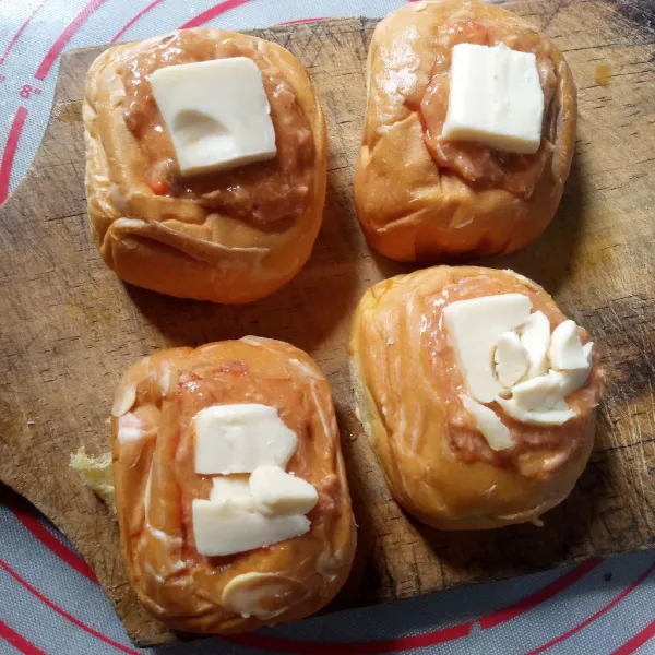 Beri topping keju mudah leleh. Olesi dasar dan permukaan bun dengan mentega tipis-tipis.