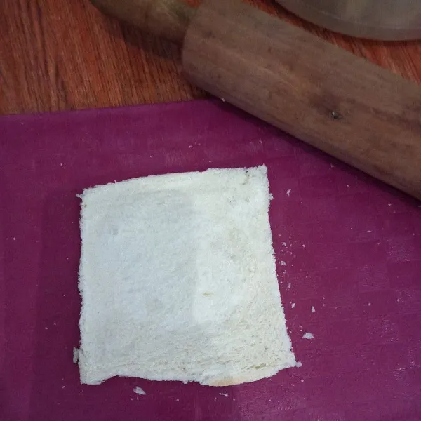 Jika menggunakan roti tawar yang ada pinggirannya buang dulu pinggiran rotinya, kemudian pipihkan roti tawar menggunakan rolling pin hingga tipis.