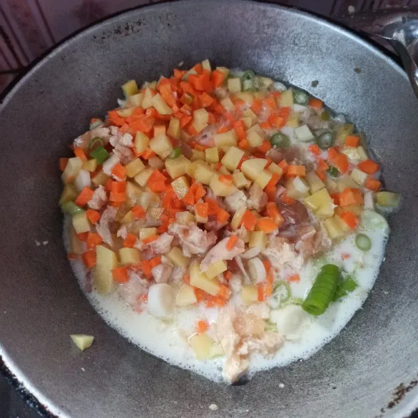 Setelah bumbu matang, masukkan daun bawang, kentang, wortel dan ayam suwir, aduk rata kemudian masukkan susu cair, masak hingga sayur matang.