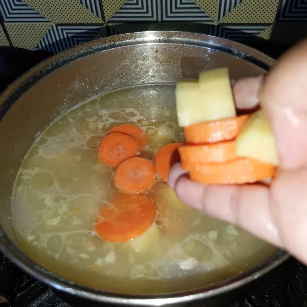 Tuang air dan tambahkan kentang dan wortel, masak sampai matang.