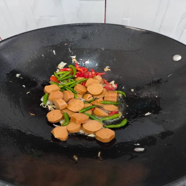Lalu tambahkan sosis dan cabe rawit utuh, aduk rata.