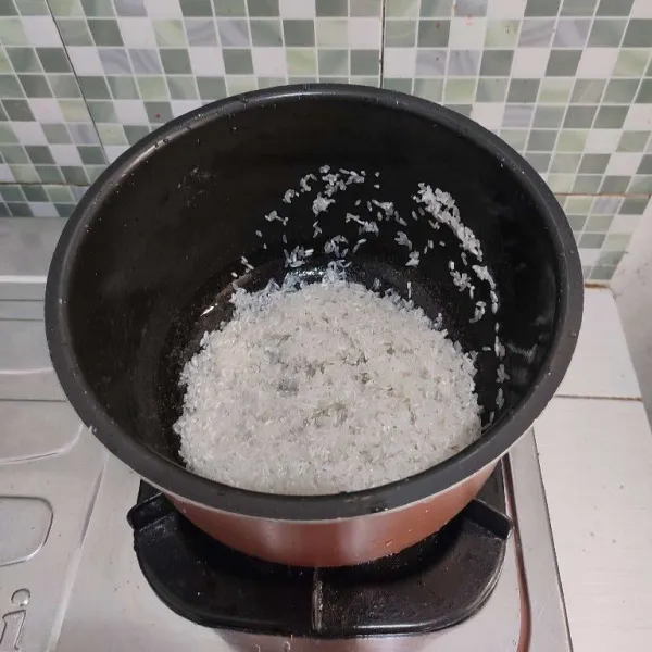 Cuci bersih beras, tuang ke dalam wajan rice cooker.