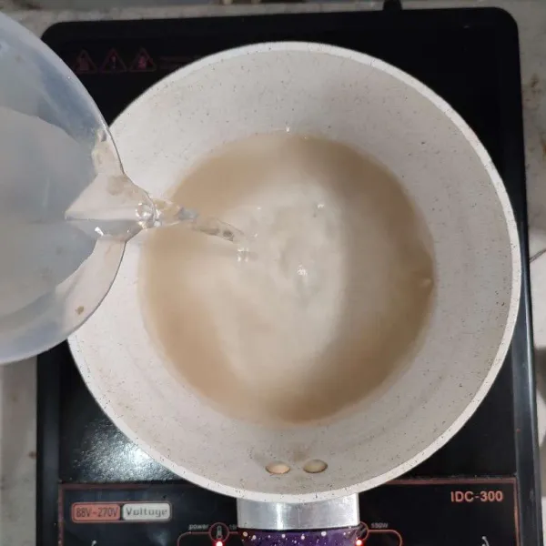 Masukkan agar-agar dan vanili ke dalam milk pan, lalu tuang air ke dalamnya, aduk rata.