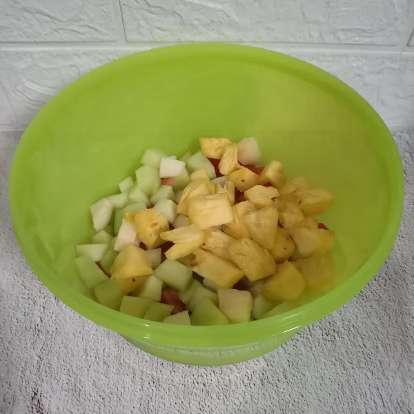 Potong buah-buahan dan masukkan ke dalam wadah.
