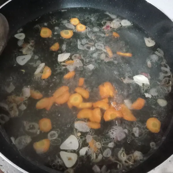 Rebus air sampai mendidih lalu masukkan bawang goreng dan wortel.
