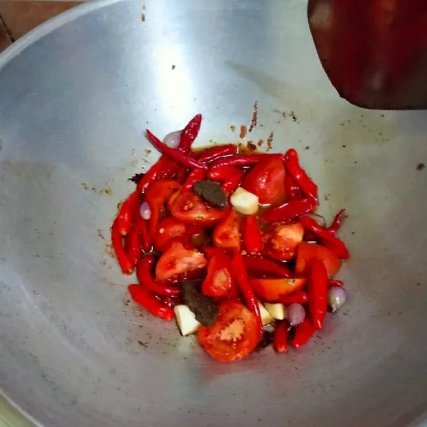 Panaskan minyak goreng, lalu masukkan bawang merah, bawang putih, cabai merah keriting, cabai rawit, tomat merah, dan terasi.