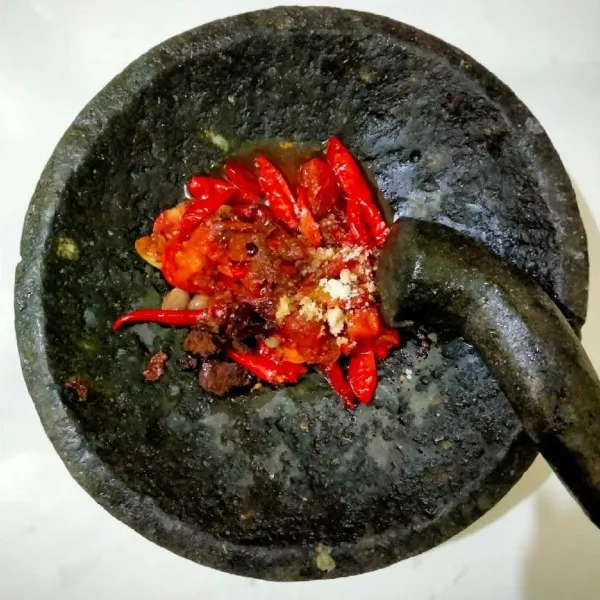 Siapkan cobek, lalu masukkan bahan sambal yang sudah digoreng tadi, beri garam, kaldu jamur, dan sedikit gula merah.