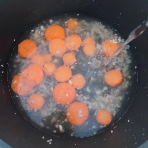 Masukkan potongan wortel dan air, rebus hingga empuk.