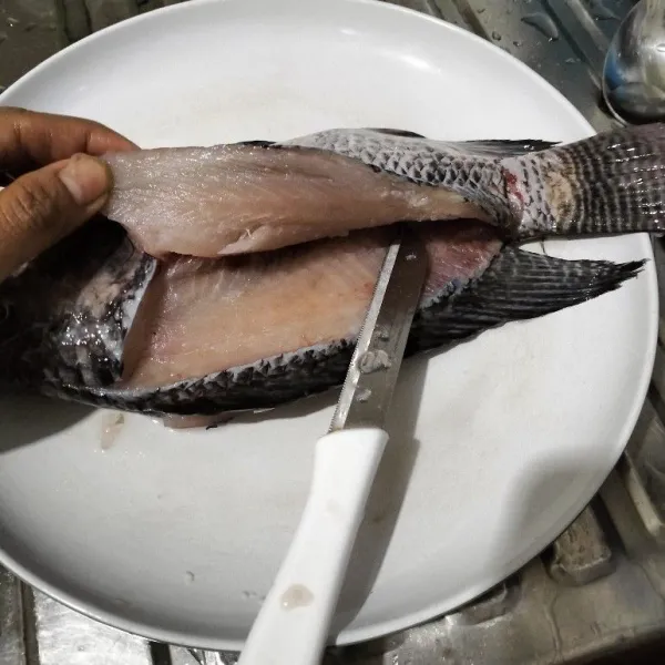 Lalu sayat daging ikan sisi kanan dan kiri ikan, membentuk sayap dari ekor hingga kepala. Tapi jangan putus. Pakai pisau kecil yang tajam.