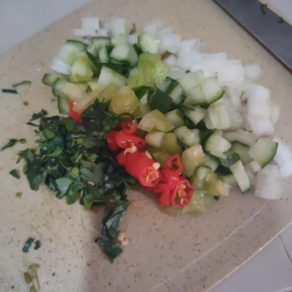 Buang bagian tengah pada zukini dan tomat hijau, kemudian potong dadu, potong juga cabe merah, bawang bombay dan daun kemangi.