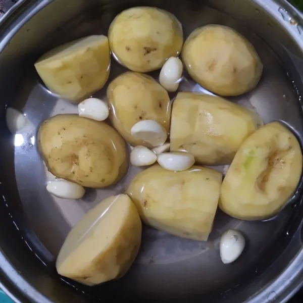 Kupas kentang dan bawang putih.