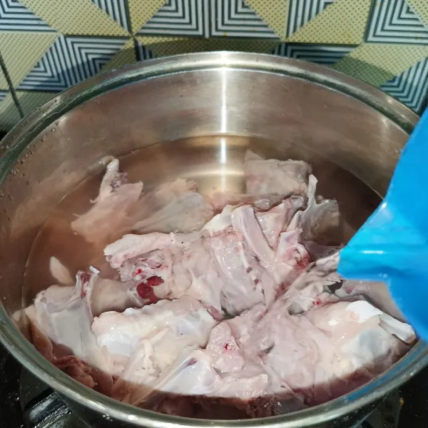 Rebus balungan ayam dan air sampai mendidih, lalu buang air rebusannya.