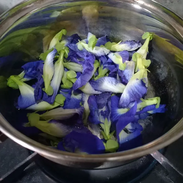 Masukkan bunga telang ke dalam panci. Kemudian tuang air.